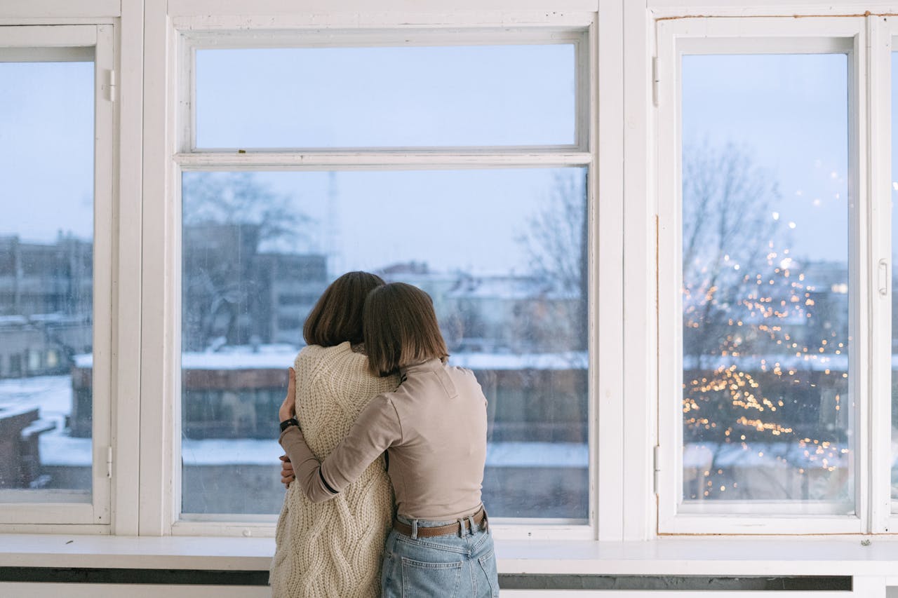 Two people embracing looking out a window